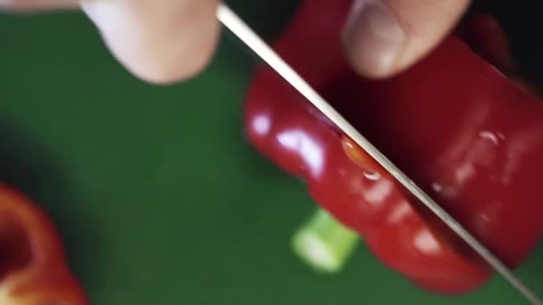 Ansicht von oben: Paprika wird mit Messer auf grünem Küchentisch geschnitten. — Stockvideo