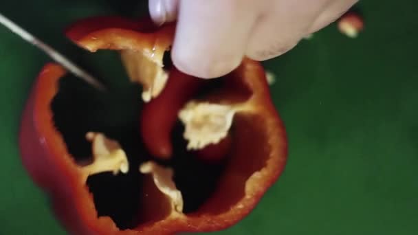 Primer plano de pimentón rojo pimienta se está cortando con un cuchillo en la mesa de la cocina verde . — Vídeos de Stock
