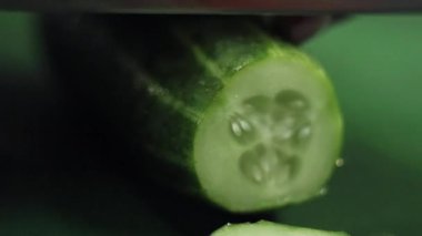 Yeşil mutfak masasında büyük keskin bıçak ile salatalık dilimleme Closeup.