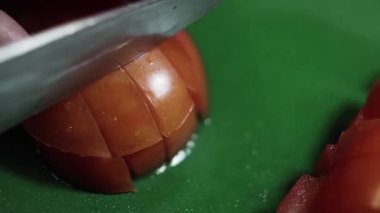 Yeşil mutfak masasında büyük keskin bıçak ile dilimlenmiş domates Closeup.