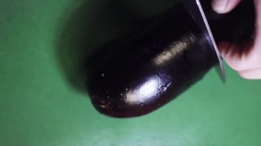 Yeşil mutfak masasında büyük keskin bıçak ile kesilmiş patlıcan üst görünümü.