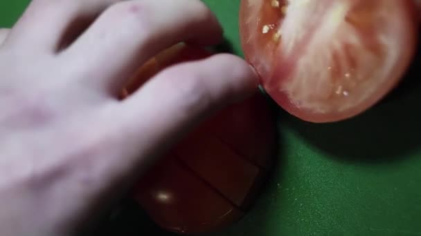 Вид зверху на помідор, який ріжеться великим гострим ножем на зеленому кухонному столі . — стокове відео