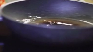 Içinde yağ olan büyük tava, soba fırını üzerinde yan yana taşınıyor