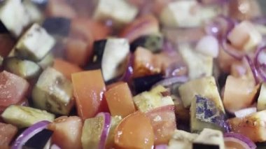 Closeup kesilmiş sebze: kırmızı domates, mor soğan ve patlıcan buğulanmış