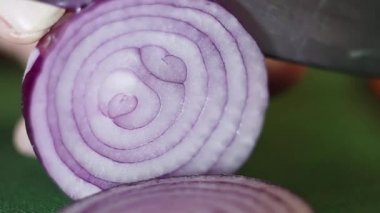 Mor soğan yeşil mutfak masasında keskin bıçak ile halkalar halinde doğranmış alır.