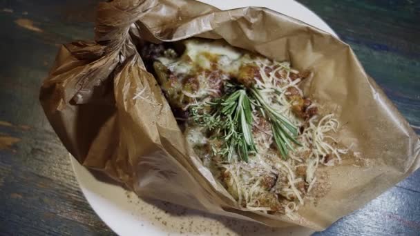 Top view of some food covered by cheese shavings, herbs and spices on wrap paper — Stock Video