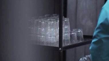 Dövmeli erkeklerin eli siyah raflardan birkaç gözlüğü çıkarıyor..