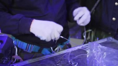 Üniformalı ve beyaz eldivenli işçiler kancalarla el ele tutuşuyorlar.