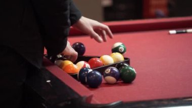 Siyah giysiler giyen bir kişi kırmızı bilardo masasında bilardo topları rafa olduğunu.