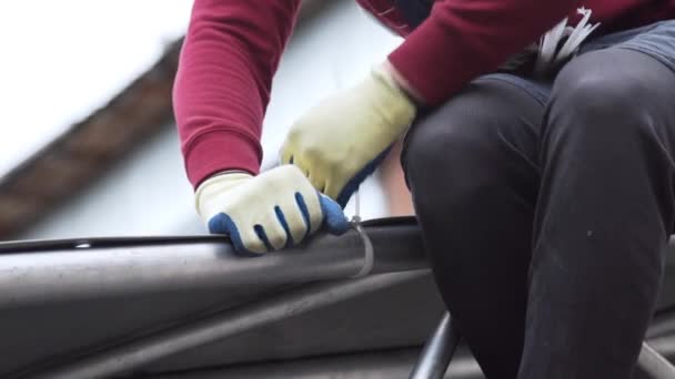 Worker fixates grey tarpaulin to aluminium structure with white plastic pins. — Stock Video