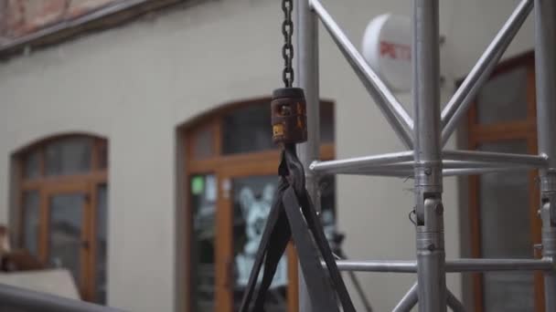 Вид на невеликий кран гак з ланцюгом, підключеним до сірої алюмінієвої конструкції . — стокове відео