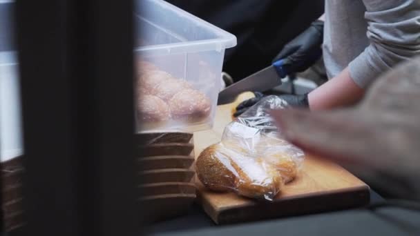 Кто-то технически режет булочки с кунжутом наполовину на деревянной доске . — стоковое видео