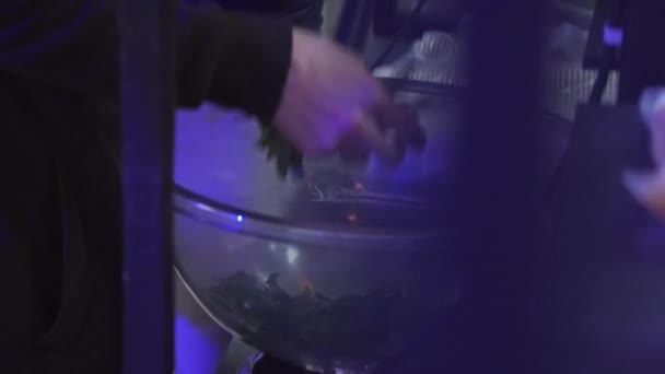 Человек в черном вынимает зеленые листья из большой круглой стеклянной чаши . — стоковое видео