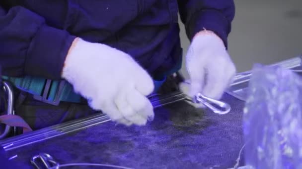 Person wearing blue outfit and white gloves holds in hands wire with snap hooks — Stock Video