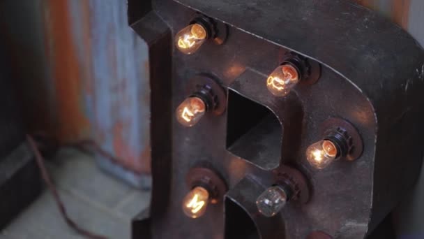 Big brown metallic letter with several orange bulb lamps mounted to it. — Stock Video