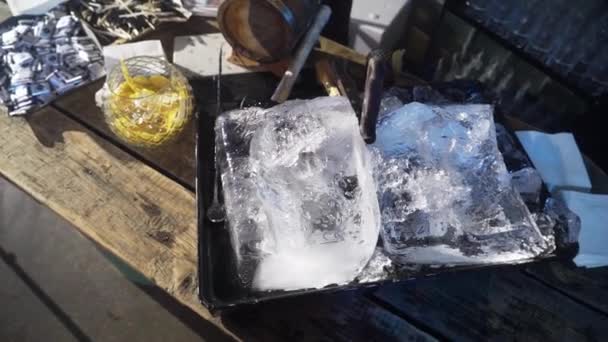 Deux énormes morceaux de glace avec couteau dans un plateau noir sont placés sur une table en bois . — Video