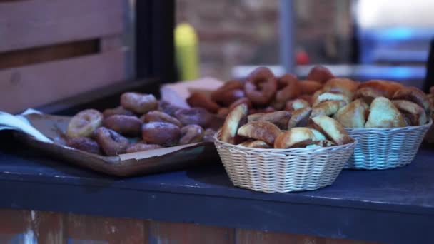 Diversi panini, pane e ciambelle sono messi in vassoio di legno e piccolo cesto . — Video Stock