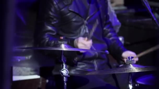 Músico masculino en ropa negra está tocando activamente la batería en el escenario con luz azul — Vídeos de Stock