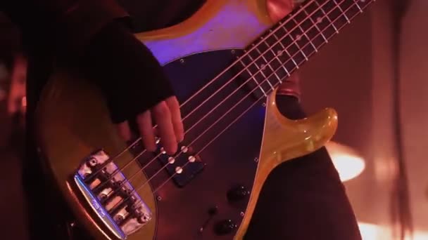 Männlicher Musiker in schwarzer Lederjacke spielt Bassgitarre auf der Bühne bei Konzert. — Stockvideo