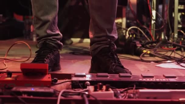 Мужские ноги в серых брюках и черных кроссовках рядом с большой гитарой . — стоковое видео