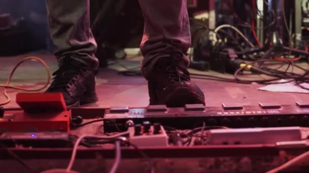 Uitzicht op mannen voeten in grijze broek en zwarte sneakers naast grote gitaar Board. — Stockvideo