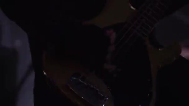 Musiker klädd i svart skinnjacka passionatle spelar basgitarr på scen — Stockvideo