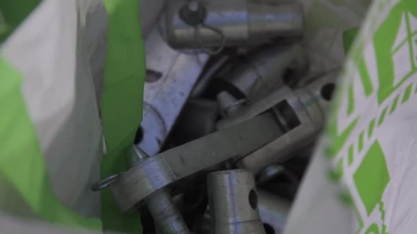 Weiß-grüne Plastiktüte voller metallischer Werkzeuge unterschiedlicher Form und Größe. — Stockvideo