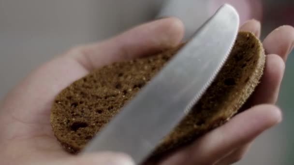 Mans hands are spreading butter on brown bran bread in kitchen in slow motion. — Stock Video