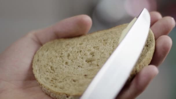 Ман руки медленно распространять масло на запрет коричневый хлеб на кухне на завтрак — стоковое видео