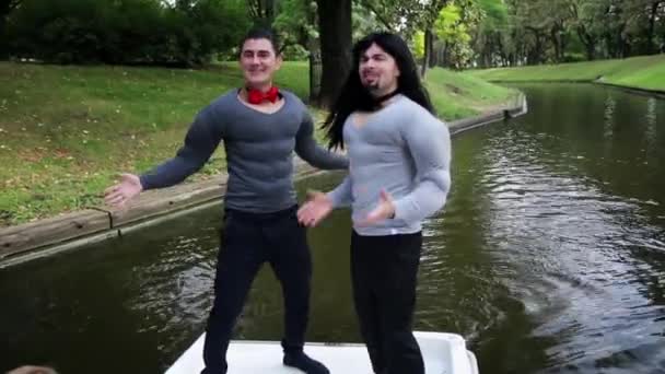 Dois homens engraçados bem-parecidos vestidos com fantasias de músculos falsos estão cantando em barco — Vídeo de Stock