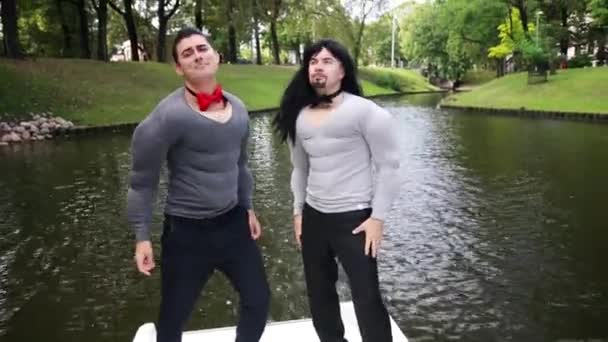 Männer in falschem Muskelshirt tanzen und singen in schwimmendem Boot — Stockvideo