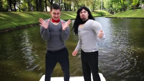 Attraktive Männer in gefälschten muskelgepolsterten Kostümen tanzen und singen im schwimmenden Boot — Stockvideo