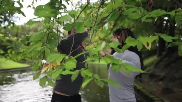 Deux beaux gars en faux costumes musculaires sur bateau flottant frappé branches d'arbre . — Video