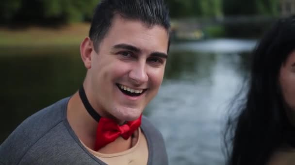 Handsome white guy in fake muscle shirt and bow tie sings in floating boat — Stock Video