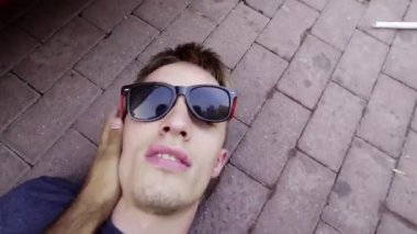 Sevimli baygın adam beton zemin üzerinde yatıyor ve tokat ile uyanmak