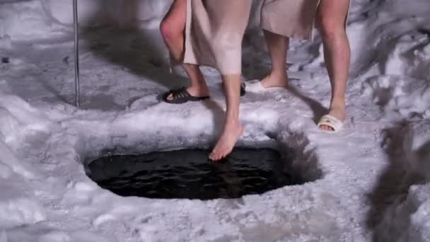 Zwei Männer mit Handtüchern um die Taille versammelten sich um Eisloch und schlugen auf Wasser ein — Stockvideo