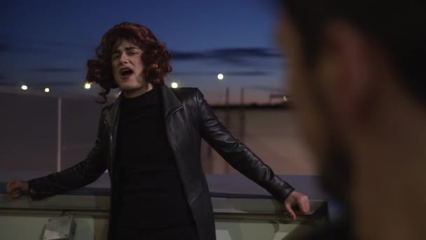 Guy klädd som kvinna med smink, klädd i svarta kläder och peruk, sjunger utanför — Stockvideo