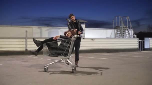 Brutal man in jacket pushes another guy dressed like woman in shopping cart. — Stock Video