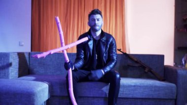 Deri ceket güzel saç kesimi ile Pretty sakallı adam kanepeye oturur ve şarkı.