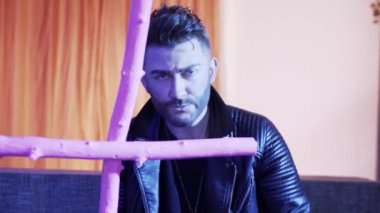 Deri ceketli çekici adam pembe haç tutan kanepede şarkı ve danslar.