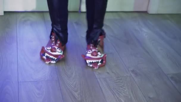 Someone wearing clown-shaped shoes and dark pants joyfully dances in room. — Stock Video