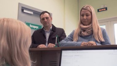 Erkek ve kadın banka binasında masa başında resepsiyonist dinler