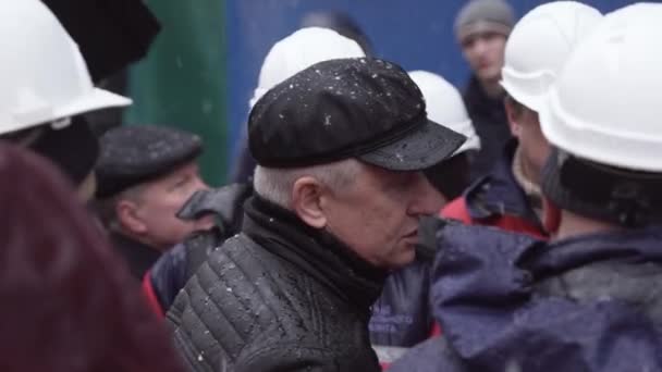 Szentpétervár, Oroszország-december 15, 2018: kaukázusi Férfi visel sapkát és fekete kabát beszél az emberek fehér sisakok — Stock videók