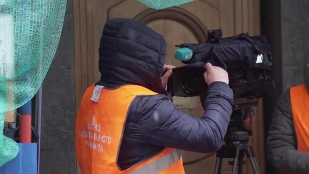 Saint petersburg, russland - dezember 15, 2018: mann mit dunkler jacke bedeckt große kamera mit kleidsärmel am schneetag — Stockvideo