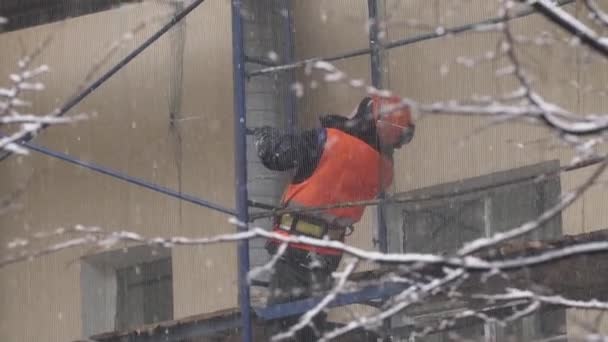 SAINT PETERSBURG, RUSSIE - 15 DÉCEMBRE 2018 : Un ouvrier portant un uniforme orange lève les yeux debout sur un échafaudage de construction — Video