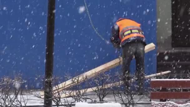 SAN PETERSBURG, RUSIA - 15 DE DICIEMBRE DE 2018: Trabajador con uniforme pobre se para en la zona de construcción, ata tablones de madera . — Vídeo de stock