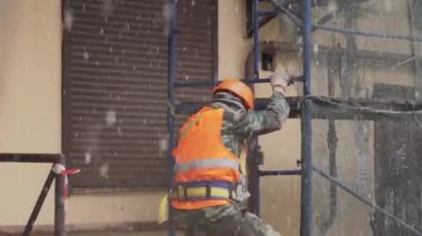 Saint Petersburg, Rusya - 15 Aralık 2018:Üniformalı ve kasklı erkek işçi inşaat iskelesinden merdivenlerden iniyor