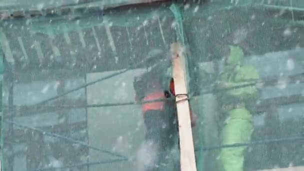 SAN PETERSBURG, RUSIA - 15 DE DICIEMBRE DE 2018: Trabajadores de la construcción se paran sobre andamios de construcción y levantan tablones de madera . — Vídeo de stock