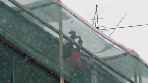 Sankt Petersburg, Ryssland-december 15, 2018: arbetare i uniform Stand på byggnadsställningar och kasta snö från taket — Stockvideo