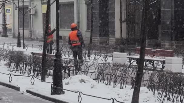 SAINT PETERSBURG, RUSSIE - 15 DÉCEMBRE 2018 : Travailleurs hommes portant un uniforme et un casque debout dans la rue le jour de neige — Video